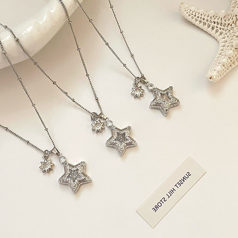 ジルコンのアクセントが付いた星をテーマにしたイヤリングと、それにマッチしたネックレスのセット。